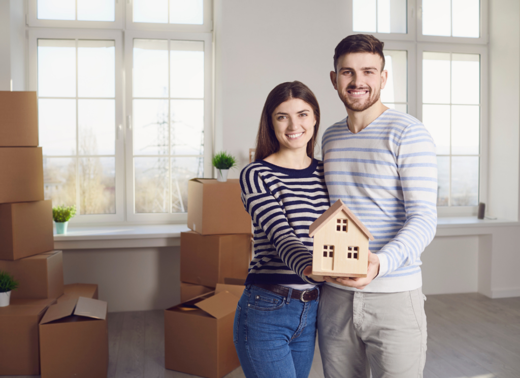 Happy couple holding a wooden structure of their dream home in their hands